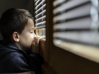 a child looking out a window with blinds